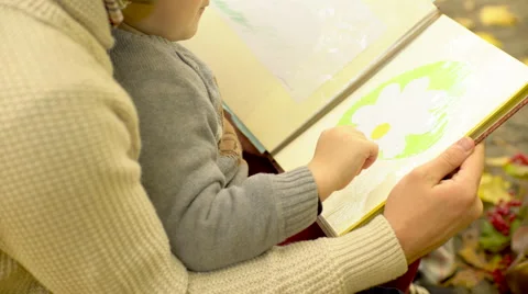 Father and his son examining drawings in album in autumn park Stock Footage 68957040