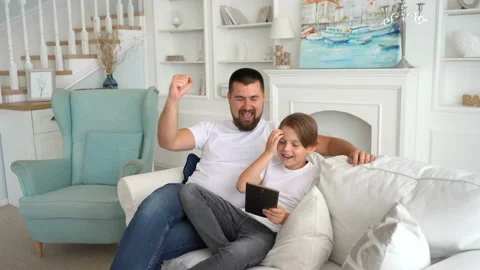 Father and his son using gadgets. Emotionally react to the game on the tablet Stock Footage 115091223