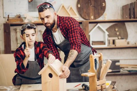 Father and his son working together in a wooden workshop, building a birdhouse Foto stock
