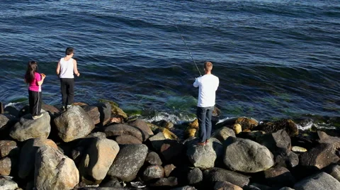 A father and his two children fishing from shore Video stock 40468606