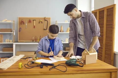 Father and little son building wooden toy house enjoy common hobby at home Stock Photos