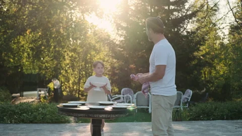 Father and son are preparing a table for dinner on the street near the house. Stock Footage 217800085
