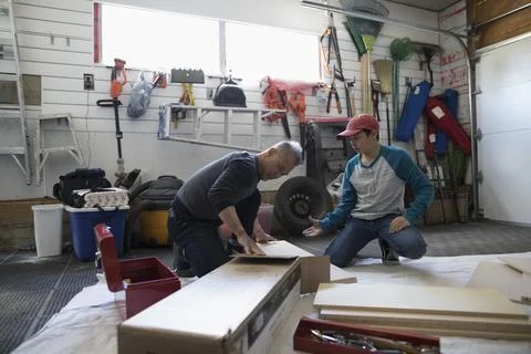 Father and son assembling flat pack furniture in garage Stock Photos