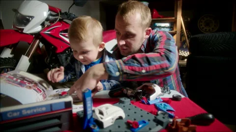 Father and Son Assembling Toy Car Using Manual Book Stock Footage 62214536