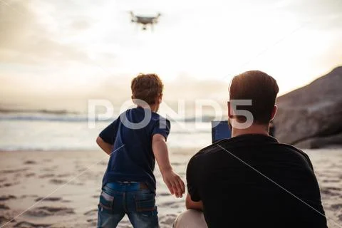 Father and son on the beach flying drone Stock Photos