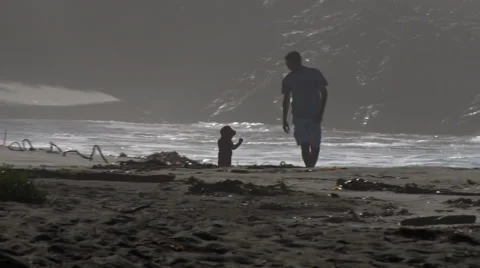 Father and son on beach playing in large surf in background during day 動画素材 42664802