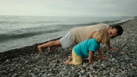Father and son on the beach playing push-ups in their arms Video stock 200807539