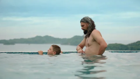 Father and Son Bonding in Infinity Pool with Tropical Mountain Ocean View. Stock Footage 338365535
