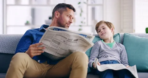 Father and son bonding, reading newspaper and relaxing on a sofa at home. Happy Stock Footage 204755448