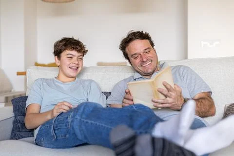 Father and son bonding while reading book at home Stock Photos