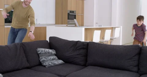 Father and son both jump onto sofa to play games console Stock Footage 49878583