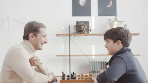 Father and son communicate while playing chess. Showing interest and intelligenc Stock Footage 233027483