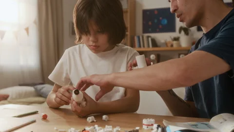 Father and Son Constructing Toy Space Rocket Model at Home Stock Footage 336175398