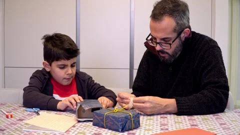 Father and son decorating Christmas gift boxes at home Stock Footage 345253391