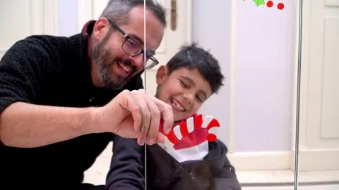 Father and son decorating a glass door for Christmas with candy canes 스톡 동영상 345253156