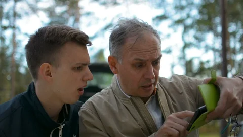 Father and son discussing a problem pointing at mobile phone and arguing outdoor 스톡 동영상 91388172