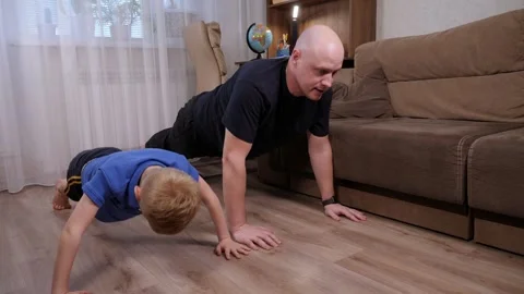 Father and son do push-ups together at home on the floor. Stock Footage 307395123