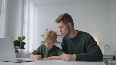 Father and son do their homework together sitting at the table in the living Stock Footage 219544123