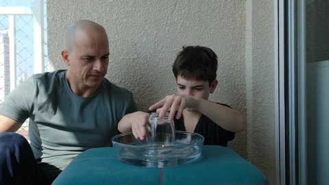 Father and son doing an experiment on the difference between atmospheric pr.. Stockbeeldmateriaal 280929801