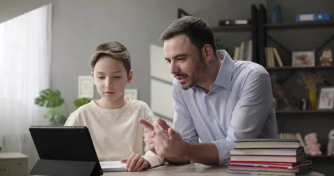 Father and son doing homework together at home desk. Father helping son Stock Footage 268057515
