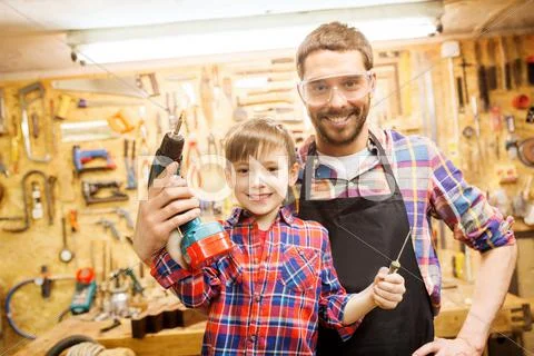 Father and son with drill working at workshop Stock Photos