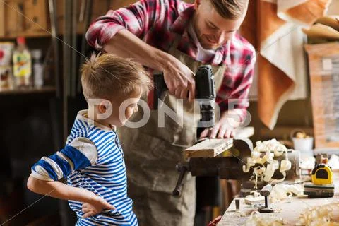 Father and son with drill working at workshop Stock Photos