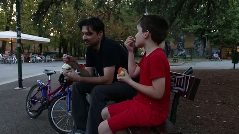 Father and son eating ice cream in park Stockbeeldmateriaal 80299701