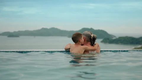 Father and Son Enjoying Infinity Pool with Tropical Ocean and Mountain View. Stock Footage 338370961