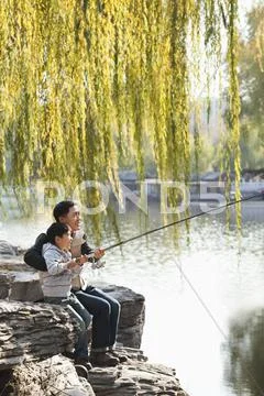 Father and son fishing together at lake Stock Photos