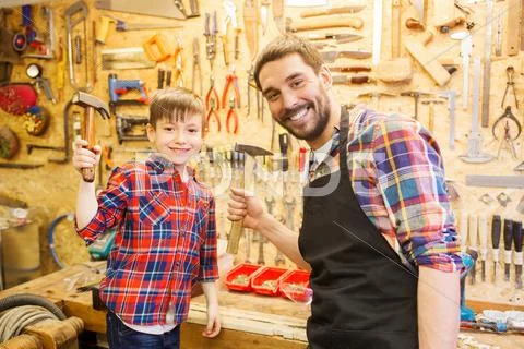 Father and son with hammers working at workshop Stock Photos