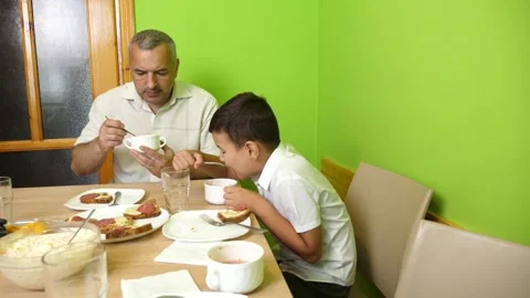 Father and son have dinner at the table. Home cooking dishes. Stock Footage 299845092