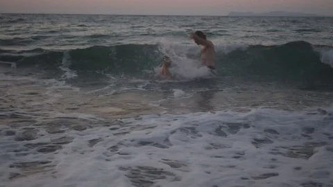 Father and son having a comic struggle - splashing each other in the waves Stock Footage 71060417