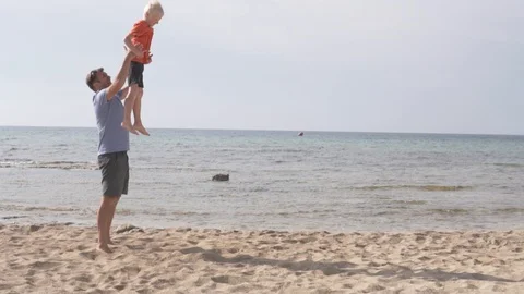 Father and son having fun on the beach at sunset, Stock Footage 110995921