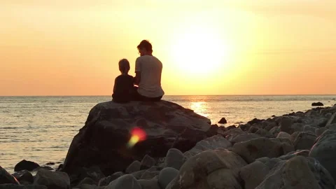 Father and son having fun at seaside silhouetted by setting sun sea background.  動画素材 129300189