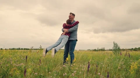 Father and son having fun on the meadow, playful spin on grass, joyful family Stock Footage 314684018