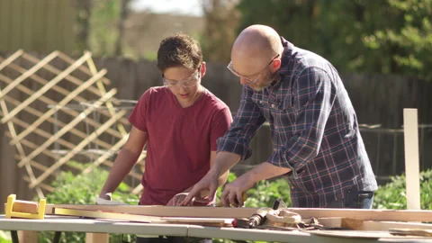 A father and son high five and laugh while working on a DIY construction project Video stock 132533910