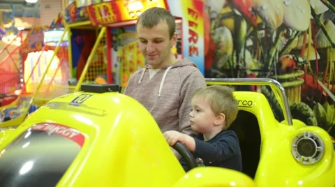 Father and son inside the toy car in the park for children amusement Stock Footage 58481802