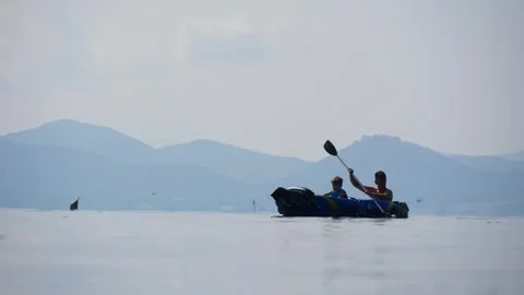 Father and Son Kayaking With a Paddle on the Calm Surface of a Mountain Lake Stock Footage 245282821