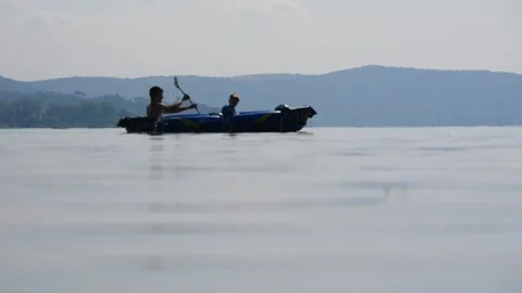 Father and Son Kayaking With a Paddle on the Calm Water Surface of a Lake Stock Footage 245283000