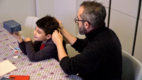 Father and son laughing while playing with Christmas gift ribbon Stock Footage 345253247