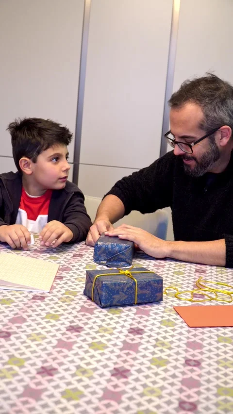Father and son laughing while wrapping gifts Vídeos de archivo 345253808
