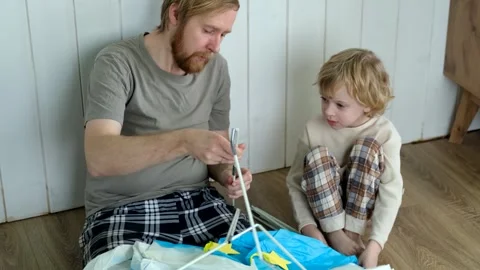 Father and son learning how to build a kids play tent at home Stock Footage 303073554