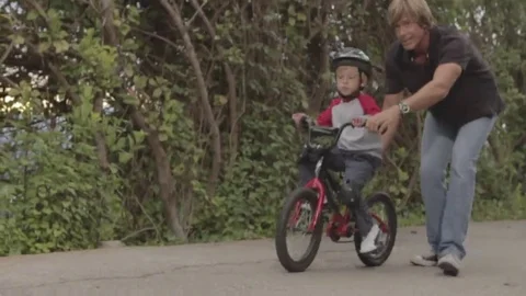 Father and son learning to ride bicycle, dad teaches kid bike riding Stock Footage 69182212