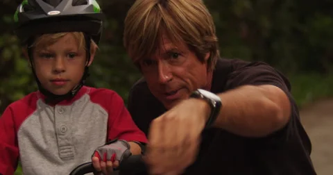 Father and son learning to ride bike, dad teaches kid bicycle riding Stock Footage 69197235