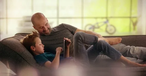 Father and son looking at Tablet on the couch Stock Footage 78664532