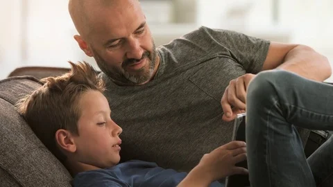 Father and son looking at Tablet on the couch. Stock Footage 78876497