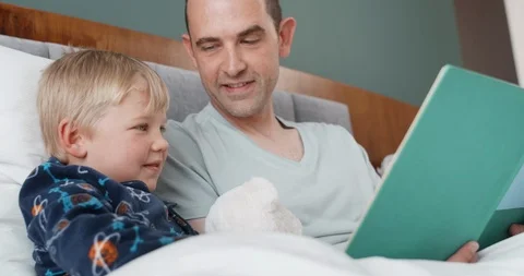 Father and son lying in bed reading Stock Footage 120362166