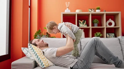 Father and son lying on sofa playing at home Video stock 237293669