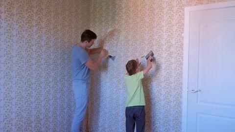 Father and son making renovation removing wallpapers from wall together. Stock Footage 129453830