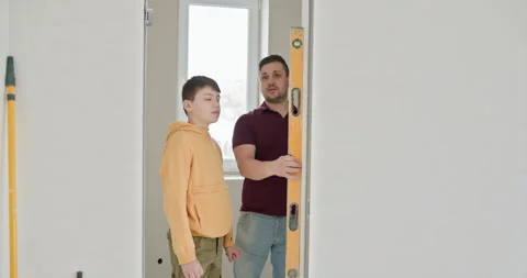 Father and Son Measuring Wall Alignment in New Home Stock Footage 273461464